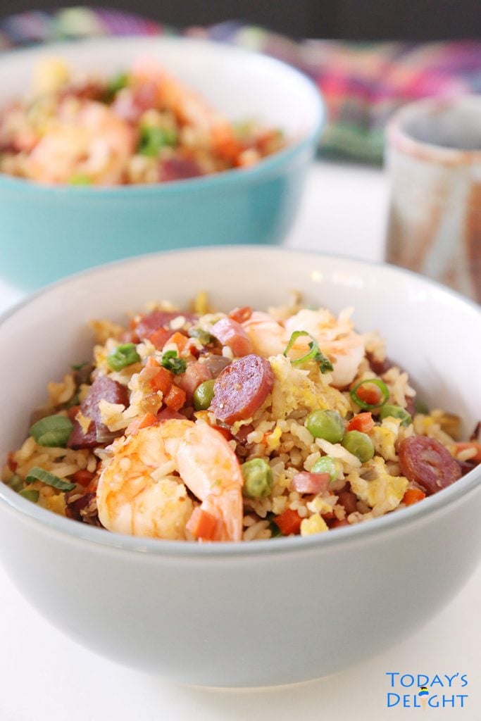 2 servings of stir fried rice with shrimp in a bowl along with tea.