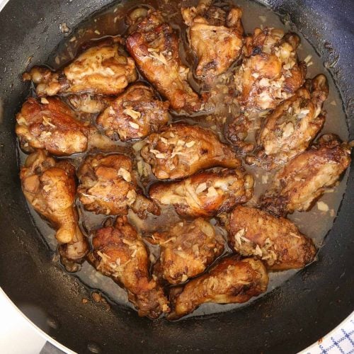 Filipino Chicken Adobo in a skillet is stewed chicken wing in vinegar garlic mixture.