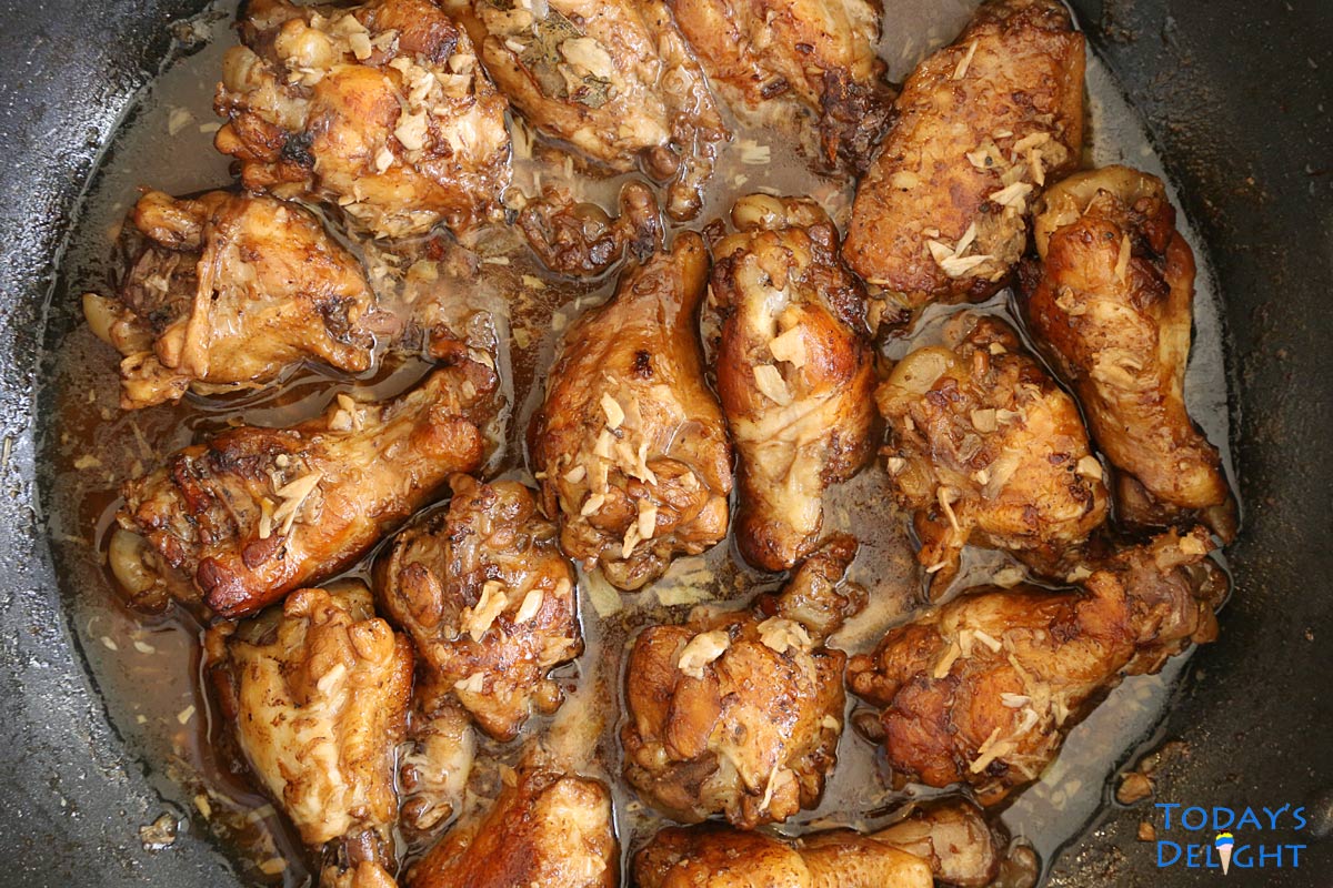 Sixteen cooked chicken wings in adobo sauce in a skillet.