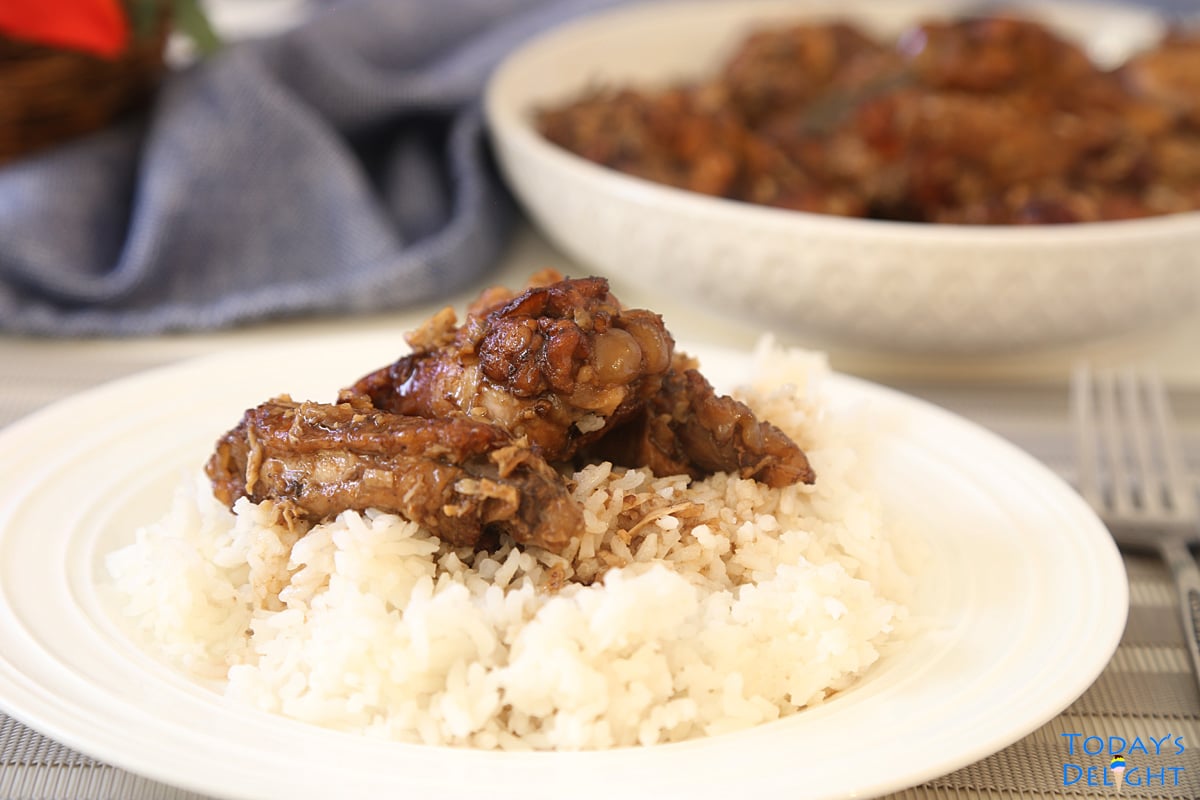 Three pieces of chicken adobo and sauce over white rice and the remaining dish in the platter.