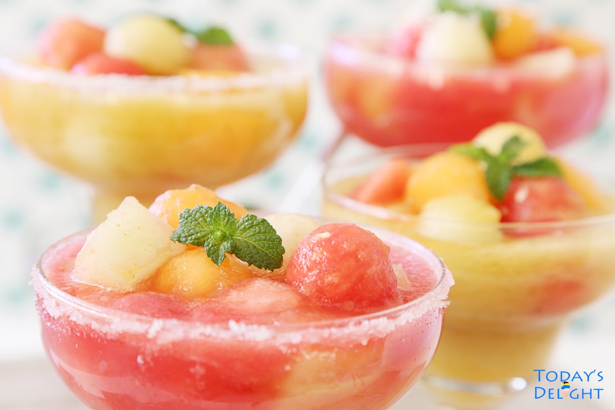 4 glasses of chilled mixed melons with juice garnish with mint.