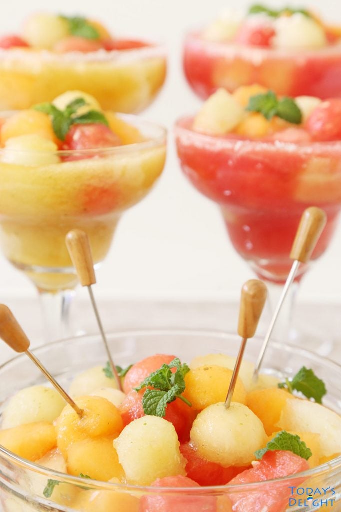 Melon ball drink in 4 margarita glasses and in a bowl with cocktail sticks.