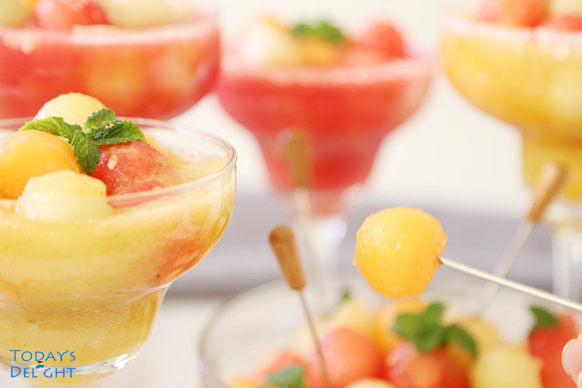 4 melon ball drink in margarita glasses and in big bowl with golden kiss melon on a cocktail stick.