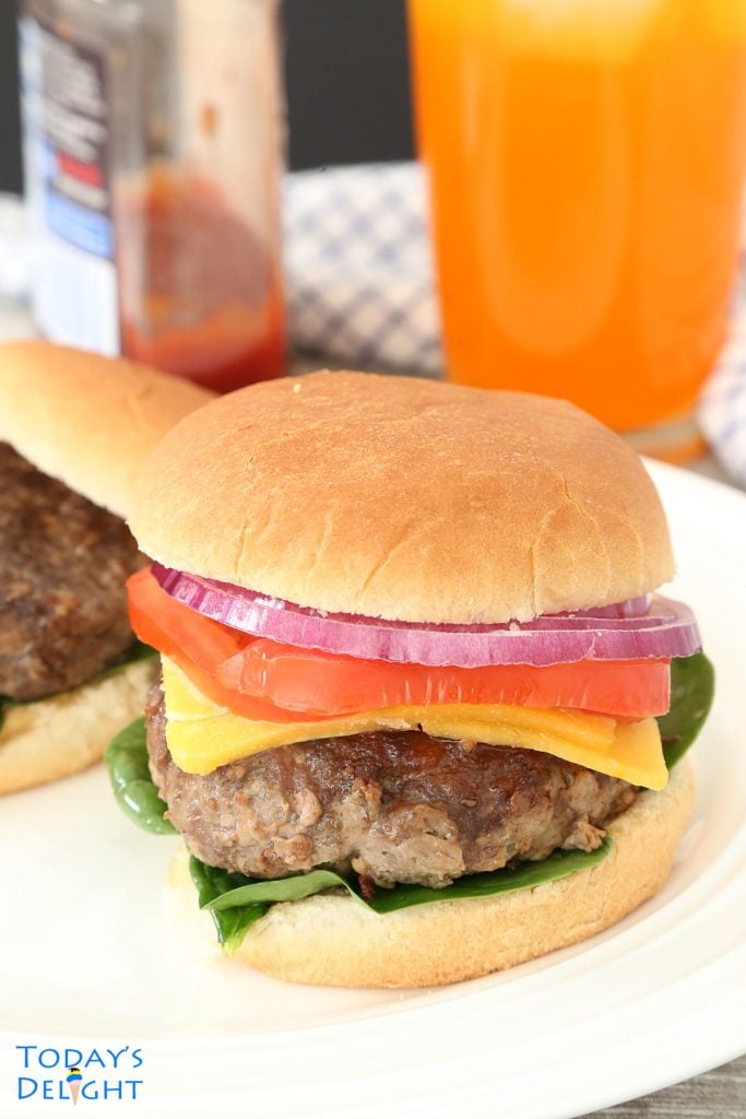 Hamburger patties in 2 buns with red onion, tomato and cheese.