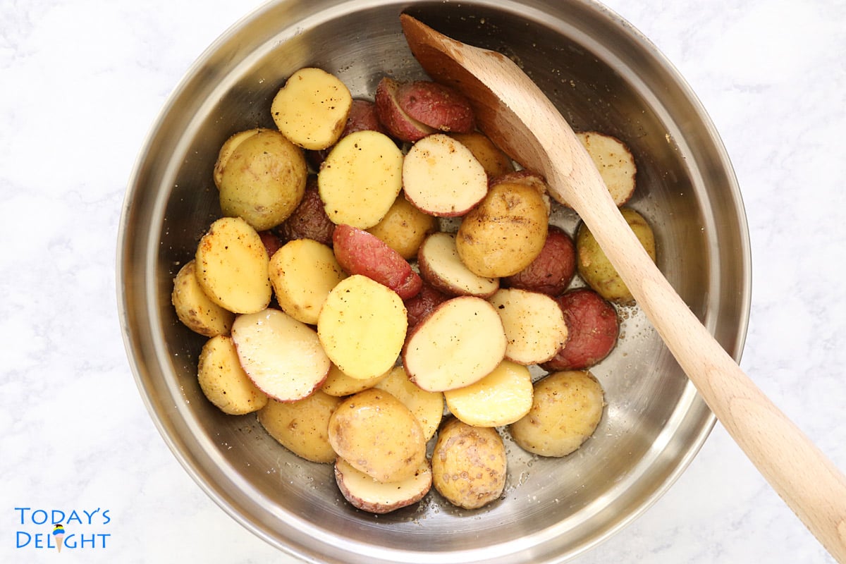 Creamer potatoes cut in half in a bowl, mixed and seasoned.