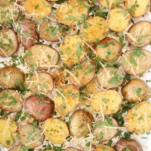Roasted Baby Potatoes in baking pan line with foil and garnished with parmesan cheese and chopped parsley.