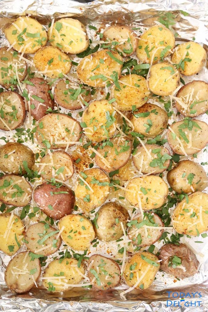 Roasted Baby Potatoes in baking pan line with foil and garnished with parmesan cheese and chopped parsley.