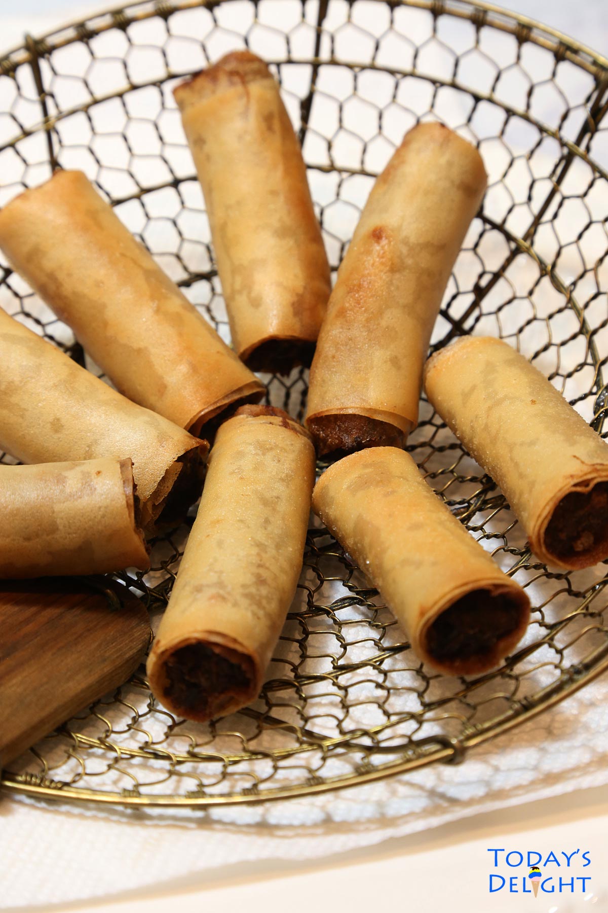 Deep fried lumpiang shanghai in a bamboo spider strainer.