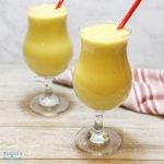 2 mango smoothie drink in hurricane glass with red straws.