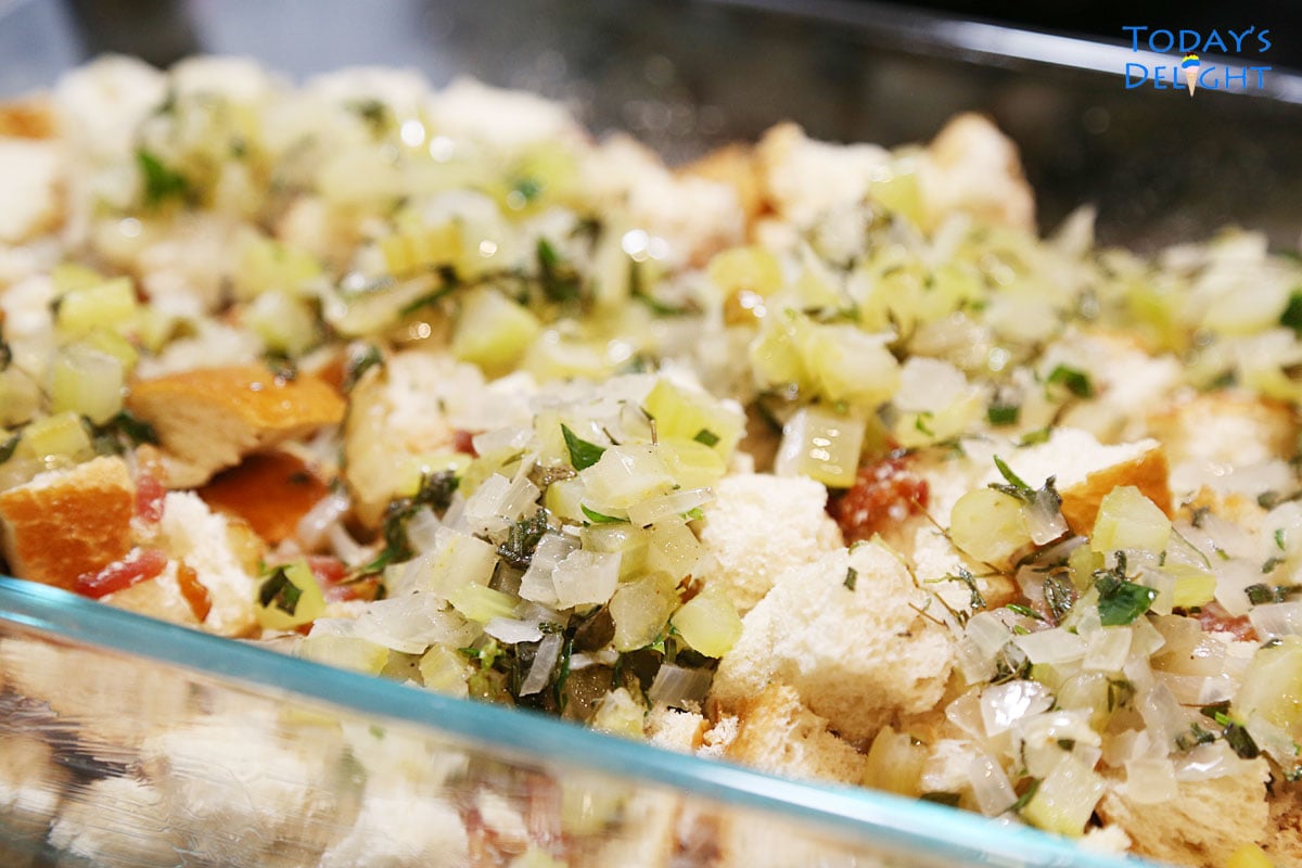 Herb, celery and butter mixture spread over dry bread cubes in casserole pan.