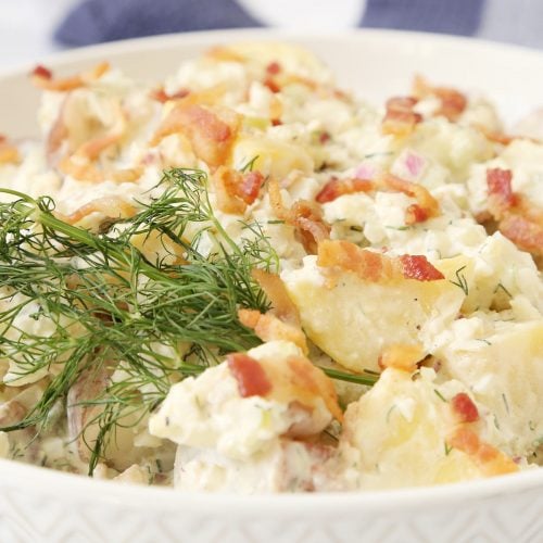 Dill potato salad garnish with bacon and dill.
