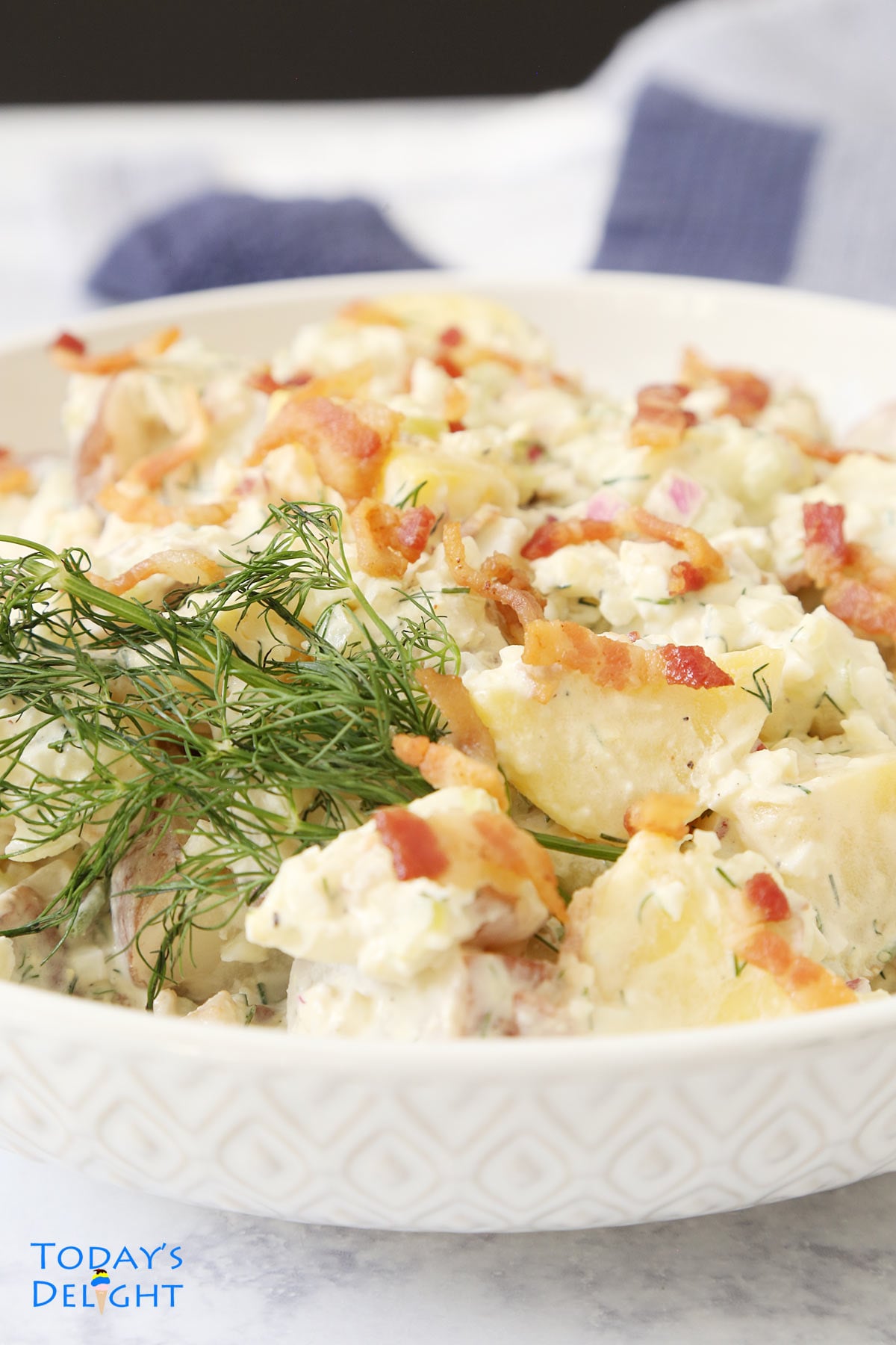 Dill potato salad garnish with bacon and dill.
