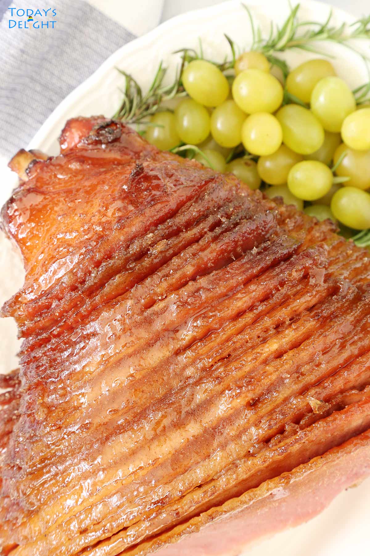 A 9 pound honey baked ham on a platter with green grapes.