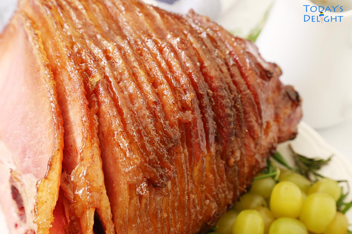 Half baked ham on a platter with green grapes.