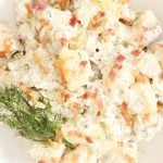 Potato salad with dill and bacon in a serving plate.