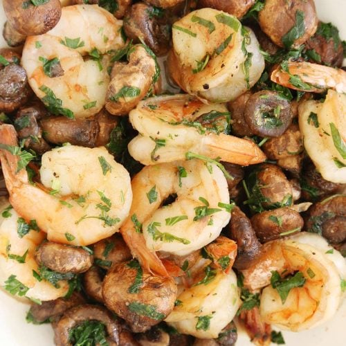 Peeled shrimp and mushroom with cilantro and parsley in a serving plate.