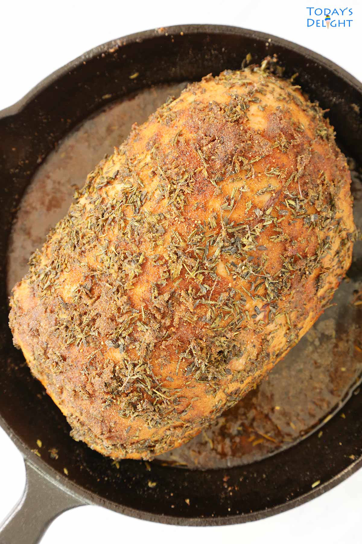 Cooked roasted boneless skinless turkey breast in a cast iron with drippings.