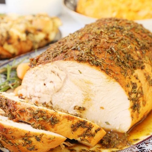 Sliced Boneless Turkey Breast Roast in a platter, turkey gravy and side dishes.