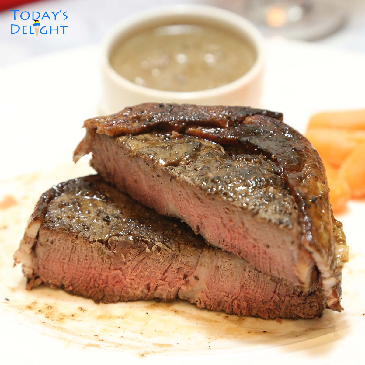 Sliced medium well steak with mushroom sauce and baby carrots on the side.