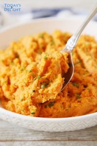 A spoonful of mashed sweet potatoes served in a shallow bowl.