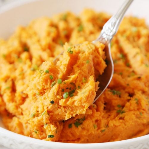 A spoonful of mashed sweet potatoes served in a shallow bowl.