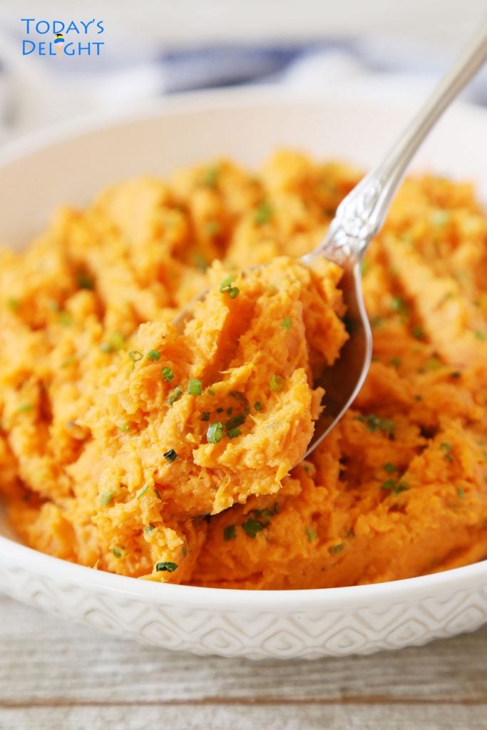 A spoonful of mashed sweet potatoes served in a shallow bowl.