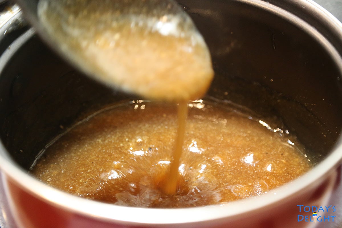 Beef broth brown gravy in a sauce pan and checking consistency with a spoon.