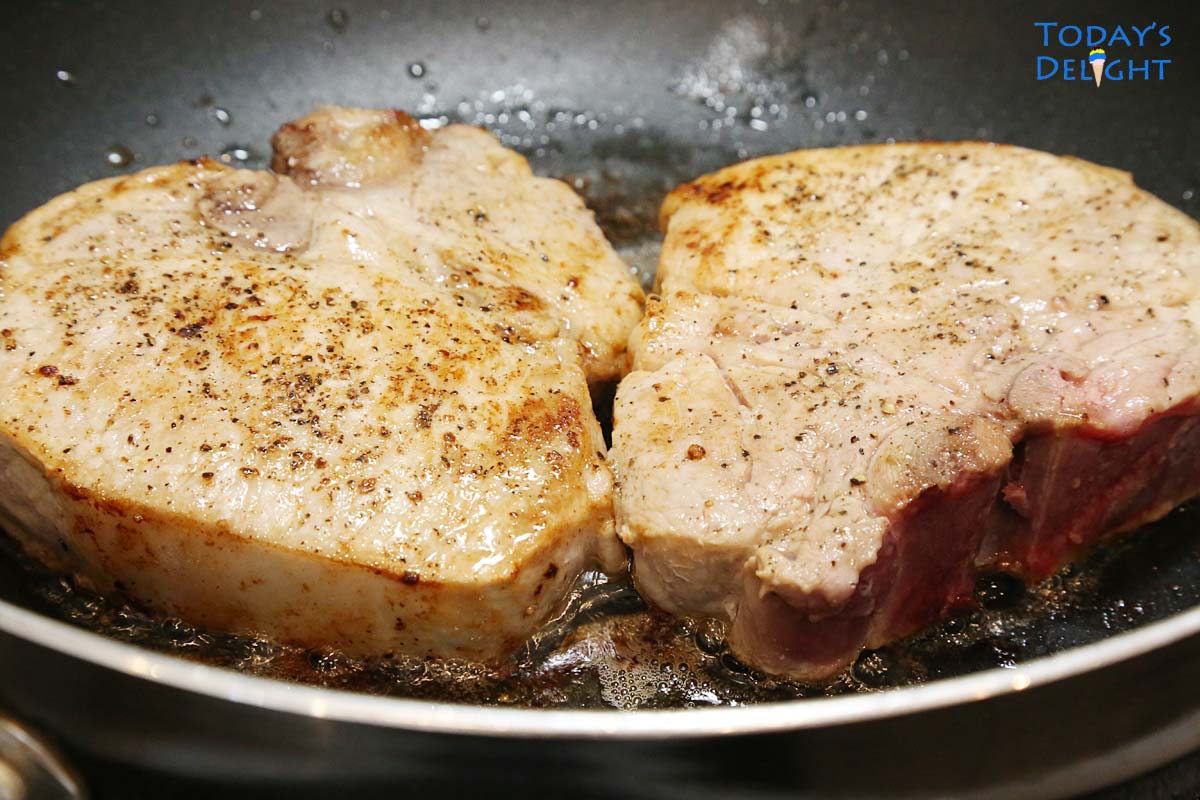 Browning two center cut loin pork chops in butter in a skillet.