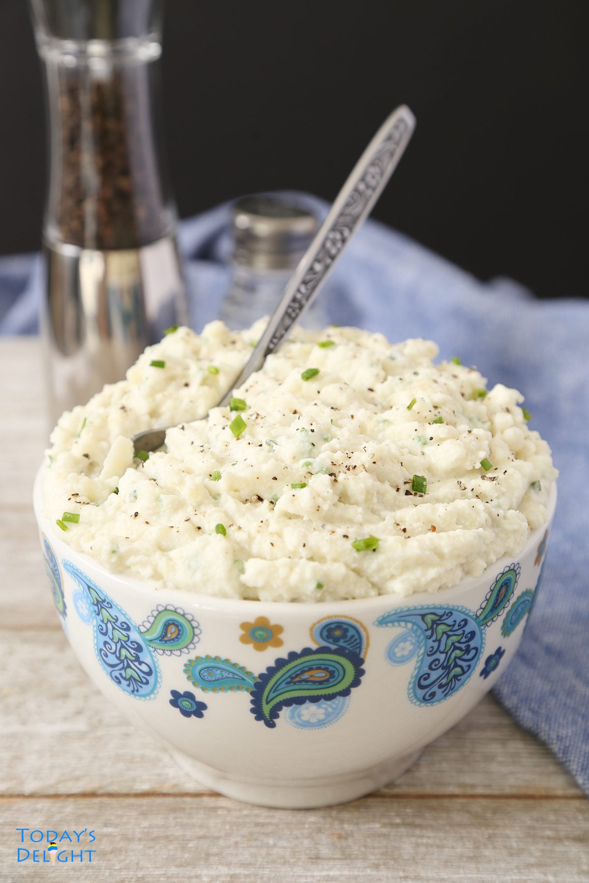 Mashed potatoes in a bowl with a spoon and salt and pepper on the side.