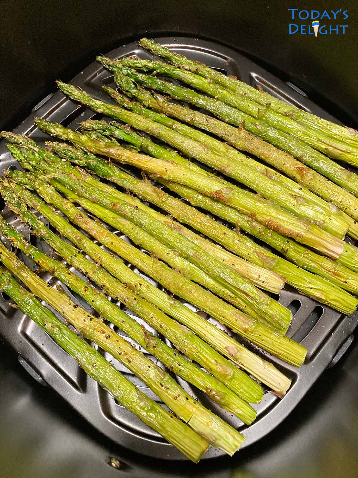 A bunch of cooked air fryer asparagus in basket.