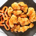 Air fried orange chicken with chopped bell peppers on a plate.