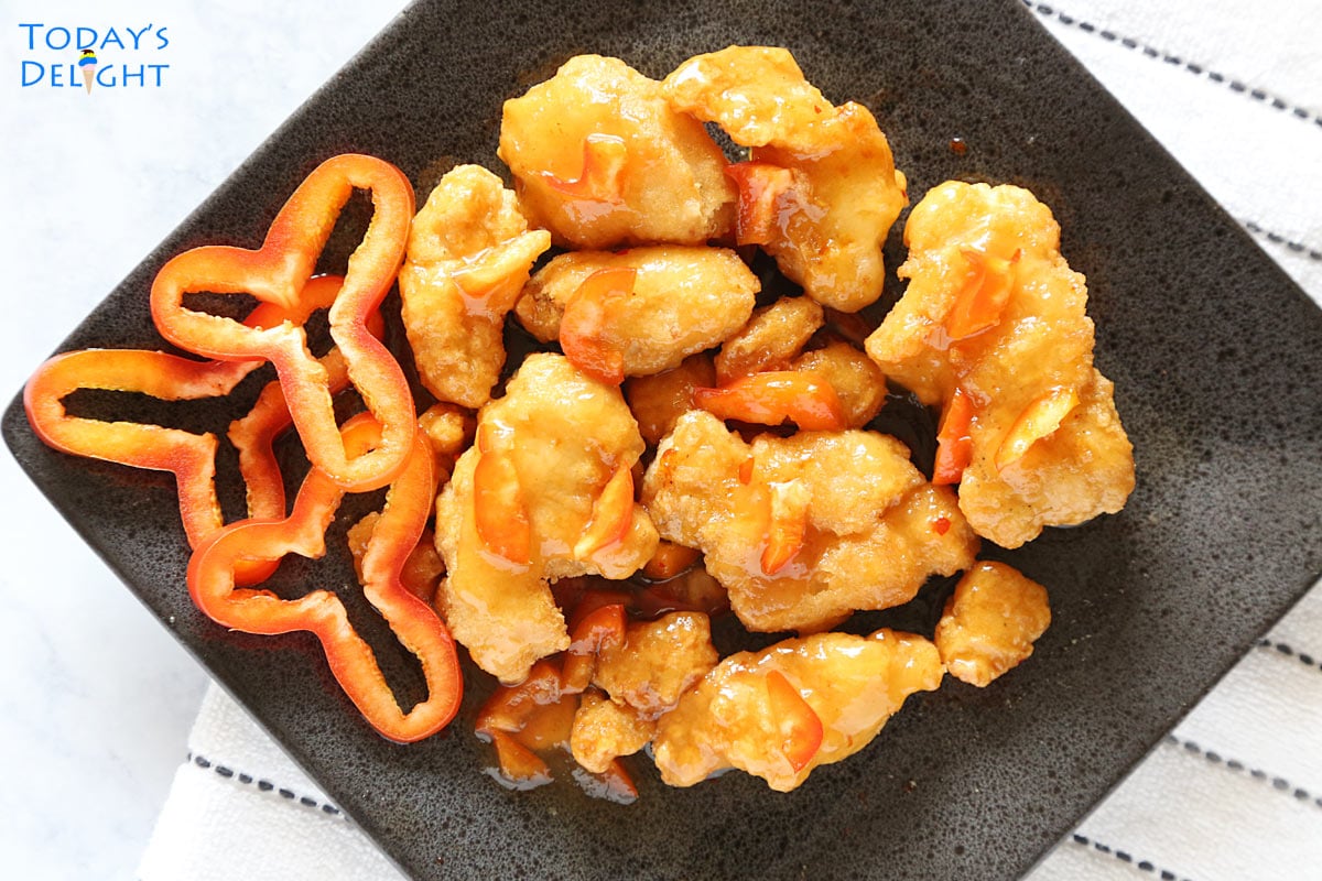 Air fried orange chicken with chopped bell peppers on a plate.