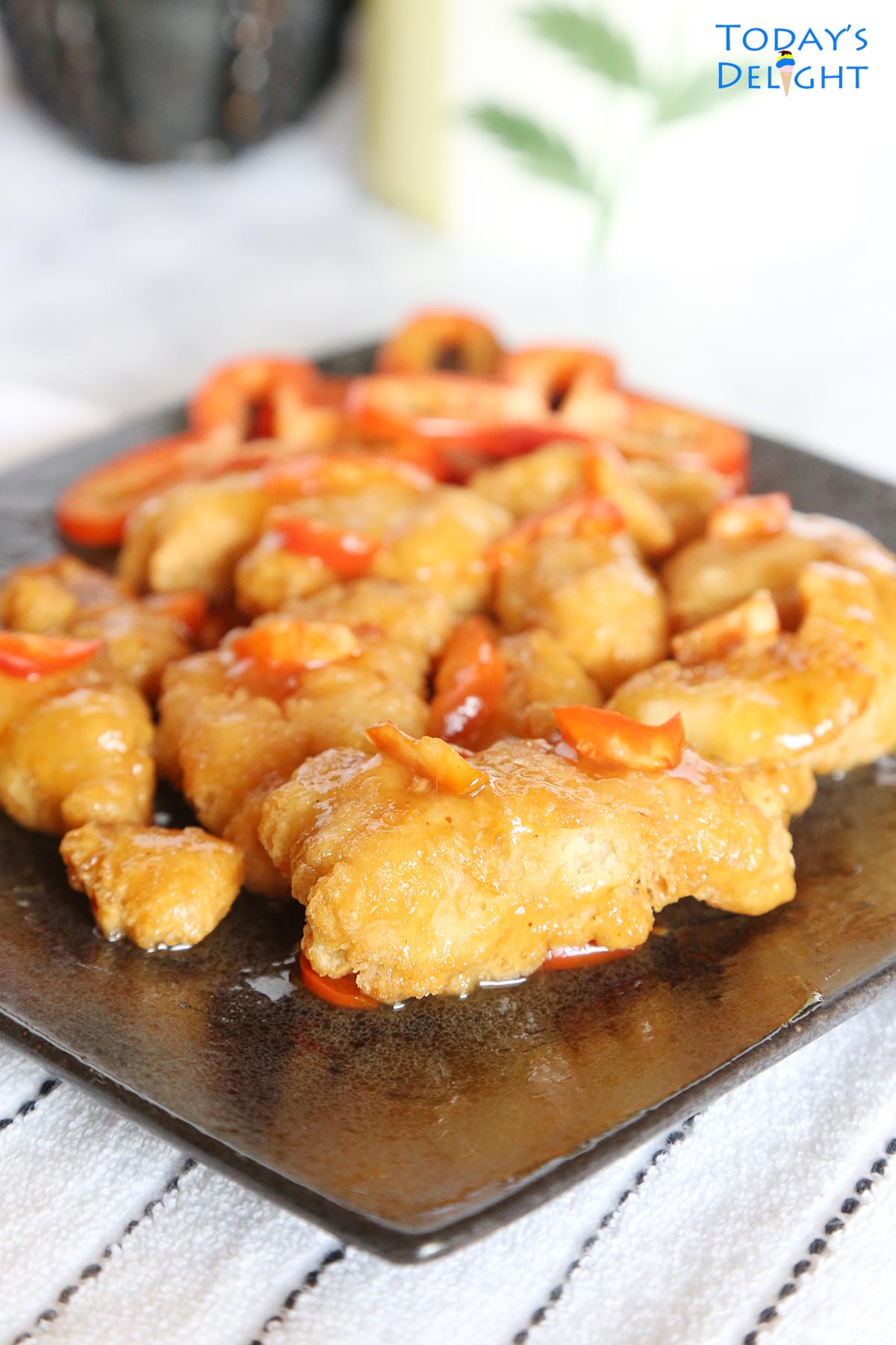 Air fried orange chicken with red bell pepper on a plate.