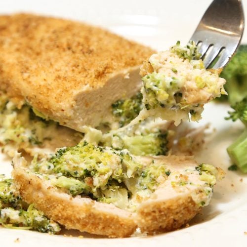 Sliced cook chicken breast filled with broccoli and cheese in a fork.