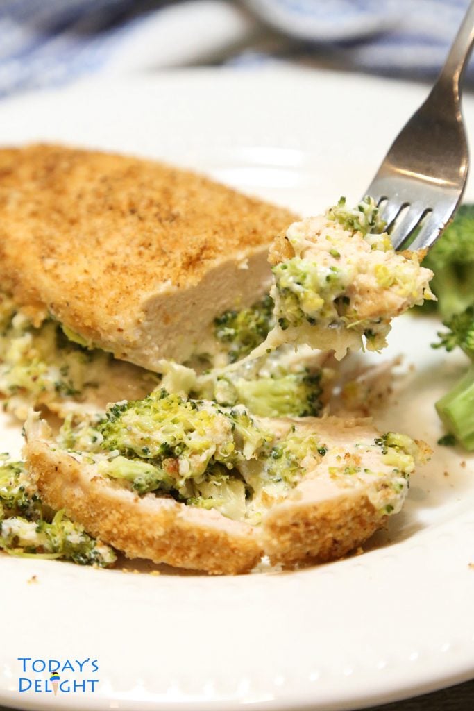 Sliced cook chicken breast filled with broccoli and cheese in a fork.
