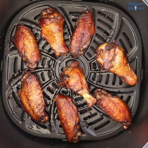 8 pieces of cooked marinated chicken wings in air fryer basket.