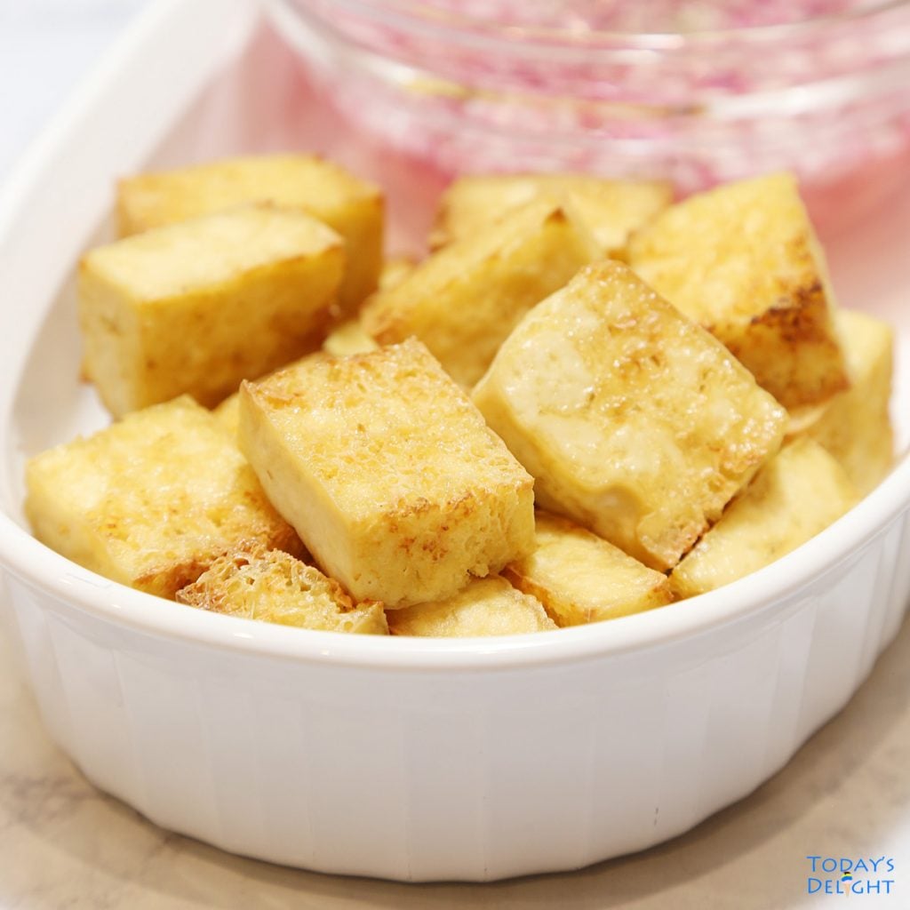 Sliced air fried tofu with vinegar and onion dip on the side.