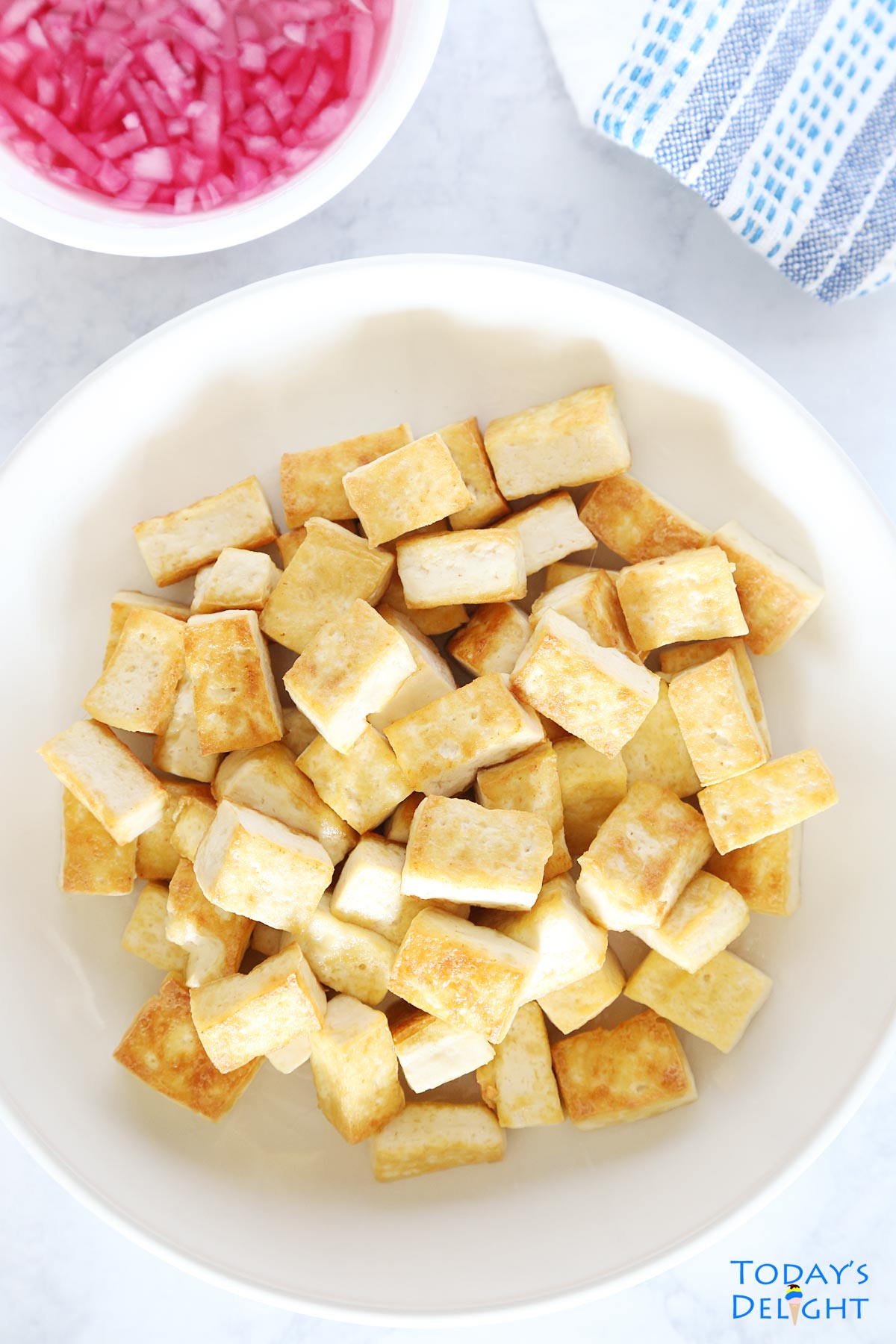 Air fried tofu on a dish and a side of vinegar and onion dip.