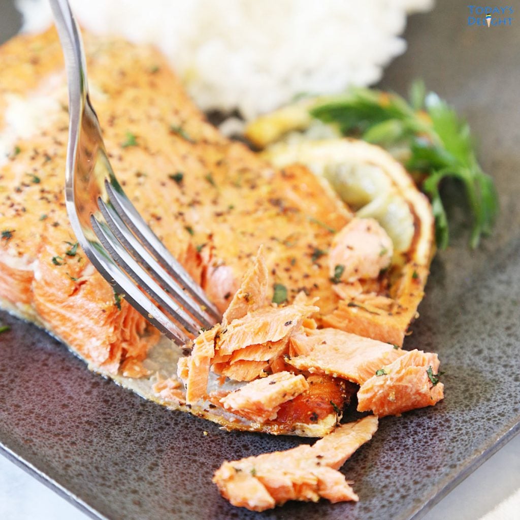 Air fried lemon pepper salmon flaked with a fork and a side of white rice.
