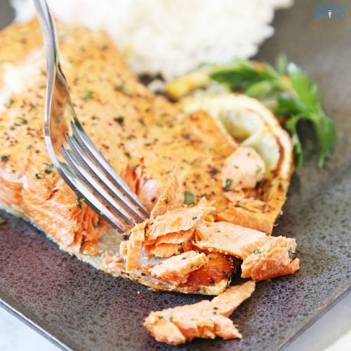 Air fried lemon pepper salmon flaked with a fork and a side of white rice.