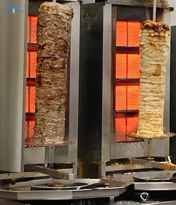 Two vertical spit with meat with heating element on the back.