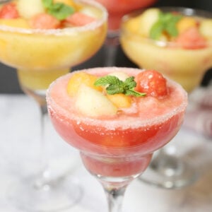Four melon ball drinks in margarita glasses rimmed with salt. Drinks are made with cantaloupe, honeydew and watermelon garnished with mint leaves.