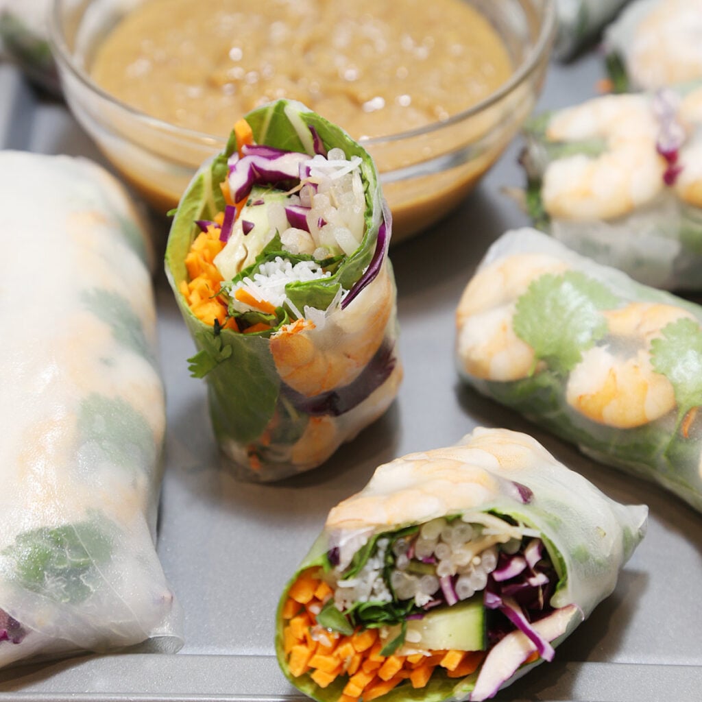 Pieces of Vietnamese fresh vegetables spring rolls with shrimp on a platter with peanut sauce.