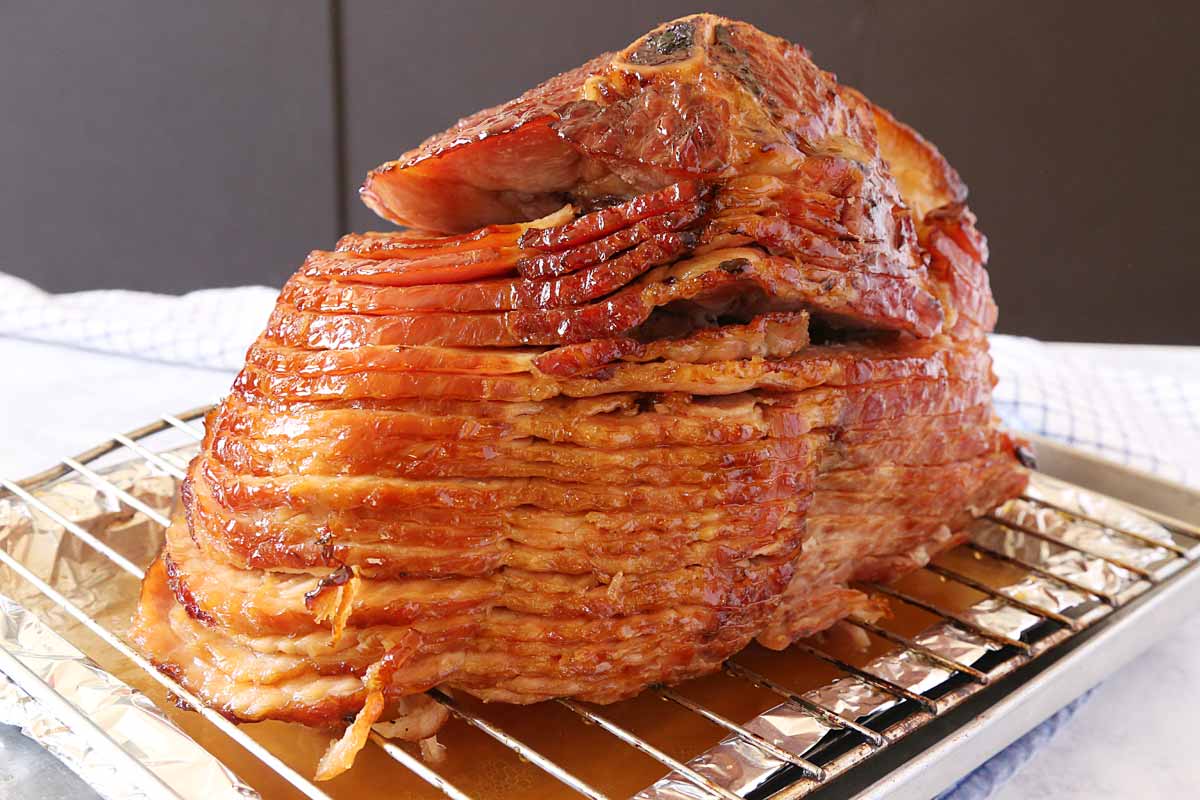 Fully cooked honey glazed ham on a roasting pan with rack.